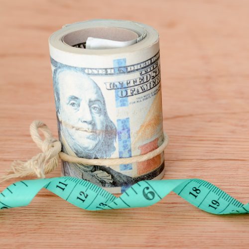 Money banknotes and green measuring tape. Expense for diet, weight loss and fasting concept